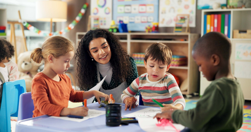 A teacher working with young students in a classroom